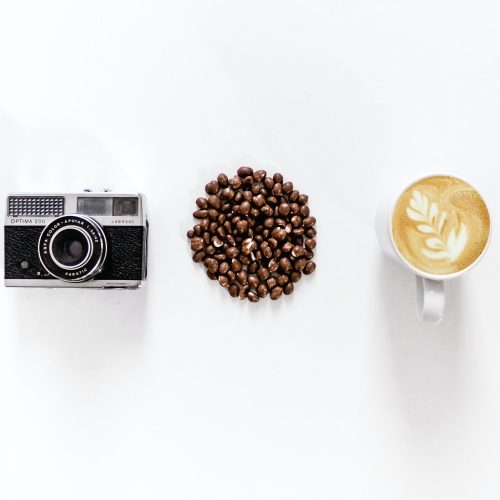 Alte Kompaktkamera, Lose Kaffebohnen und eine Tasse Café Crema