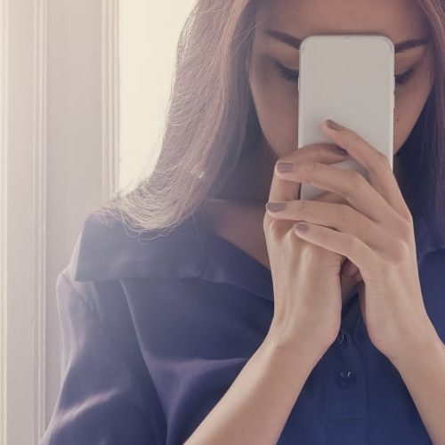 Frau hält ihr Smartphone vor ihr Gesicht